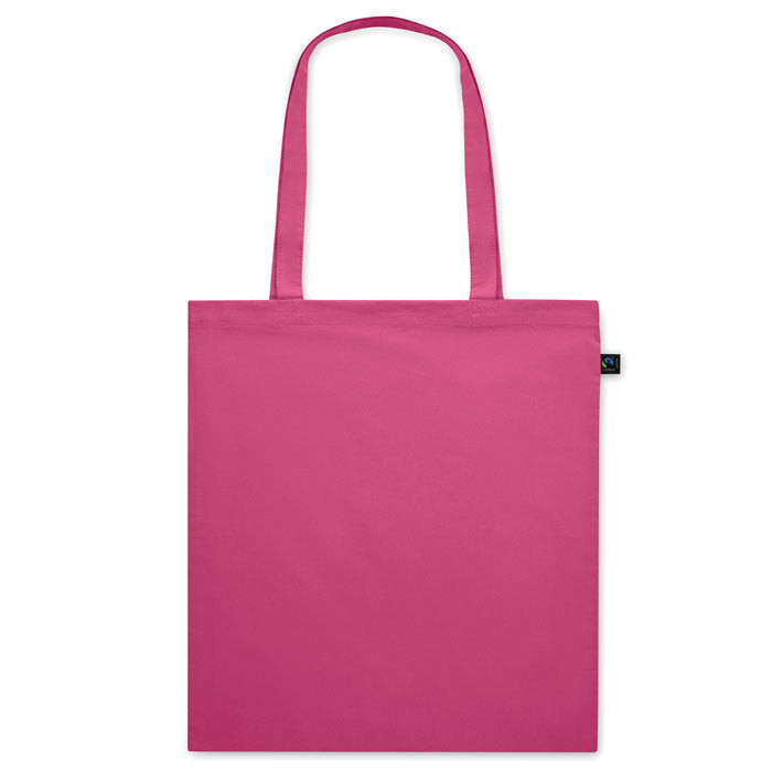 Bolsa de tela fucsia OSOLE COLOUR con etiqueta de comercio justo y asas largas. Ideal para ferias, tiendas y regalos ecológicos.
