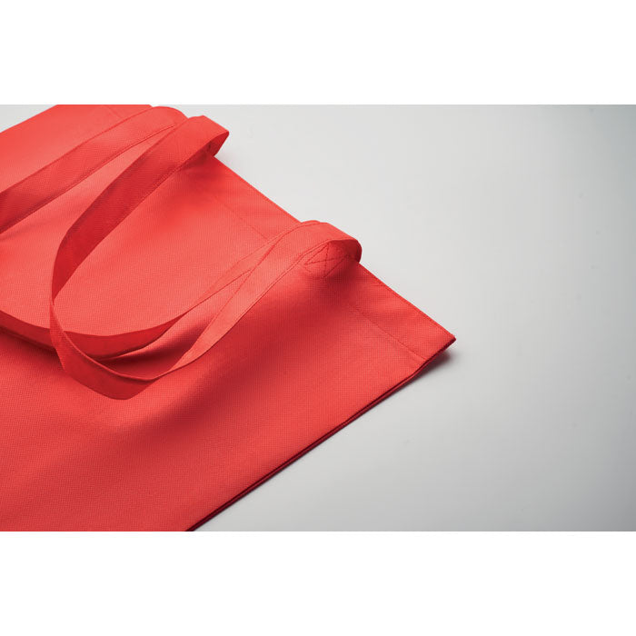 Detalle de la bolsa KAIMANI roja RPET 80 gr/m² con asas largas, mostrando su diseño ecológico y resistente para uso diario.