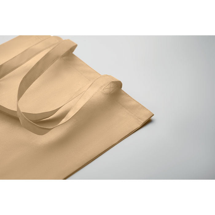 Detalle de la bolsa KAIMANI beige RPET 80 gr/m² con asas largas, mostrando su acabado ecológico y resistente para uso promocional.
