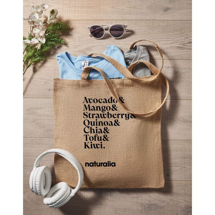 Bolsa de yute ZOLANG personalizada con texto negro, usada como bolso de compras ecológico con artículos personales en su interior.