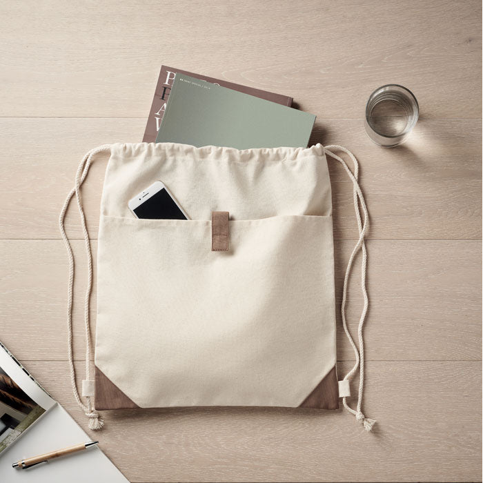 PANDA BAG natural con cuerdas y bolsillo exterior, mostrando su capacidad para llevar objetos como libros y móviles de forma cómoda.