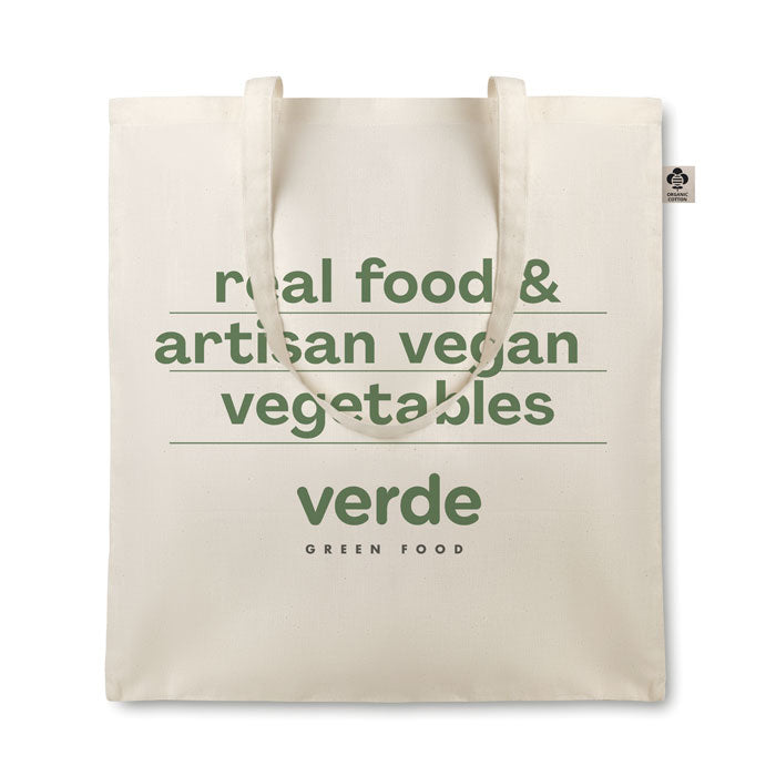 Bolsa de algodón orgánico con asas largas, diseño en color crema con texto verde sobre alimentos veganos.