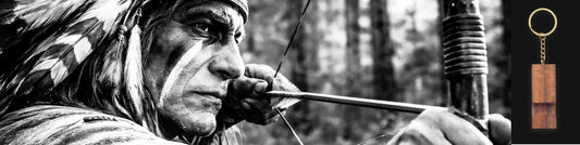 Arquero apuntando con arco hacia un llavero metálico sobre fondo oscuro