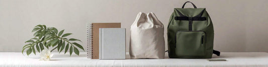 Productos de merchandising reciclado con botellas RPET, libretas hechas con cartones de bricks de leche y mochilas de algodón reciclado sobre fondo claro ecológico.