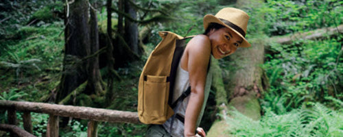 Mujer asiatica con gorro y mochila promocional en naturaleza