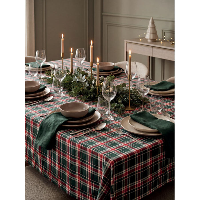 SANTABLE - Set manteles algodón en mesa decorada con velas y platos elegantes sobre mantel a cuadros.