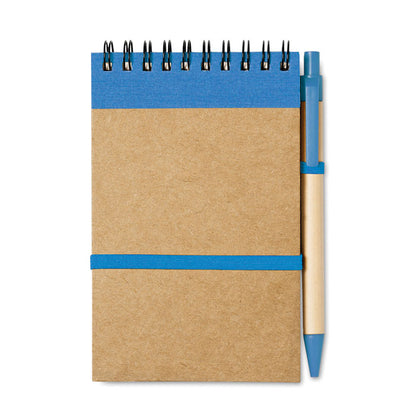 Libreta a6 con espiral en parte superior y detalles en color azul, goma horizontal de cierre y soporte para boli color azul y bolígrafo de cartón con detalles en azul