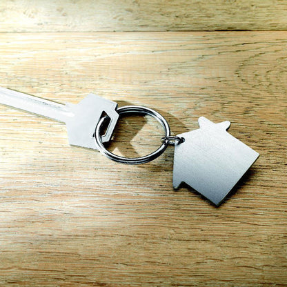 Llave con llavero en forma de casa de metal sobre una mesa de madera
