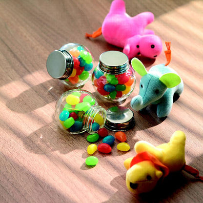 Varios botes pequeños de cristal con caramelos y peluches alrededor