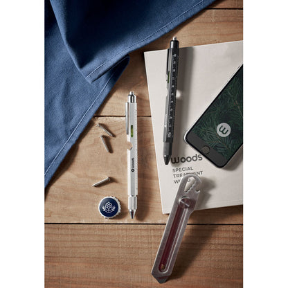 Bolígrafos con regla y nivel de metal nagro y plateado sobre mesa de trabajo con cutter, tornillos y otros accesorios