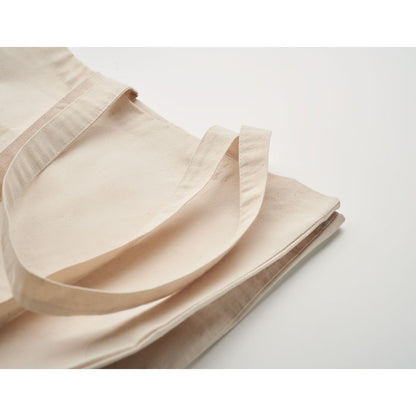 Detalle de asas cosidas y fuelle de bolsa de algodón color crudo