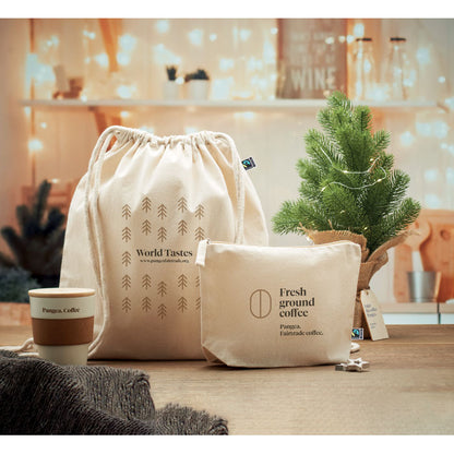 Mochila y neceser de color natural de algodón personalizados con logotipo sobre una mesa en una fotografía de ambiente navideño