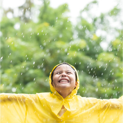 Niño con chubasquero amarillo con capucha sonriendo debajo de la lluvia