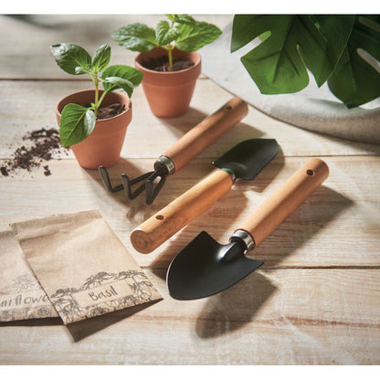 Herramientas de jardín sobre mesa de madera con plantas alrededor