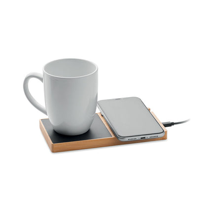 Taza blanca y móvil sobre cargador inalámbrico de sobremesa de madera con calentador de tazas