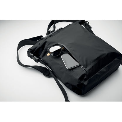 Detalle de movíl y gafas de sol dentro de bolsillo exterior con cierre cremallera de mochila negra de cierre enrrollable