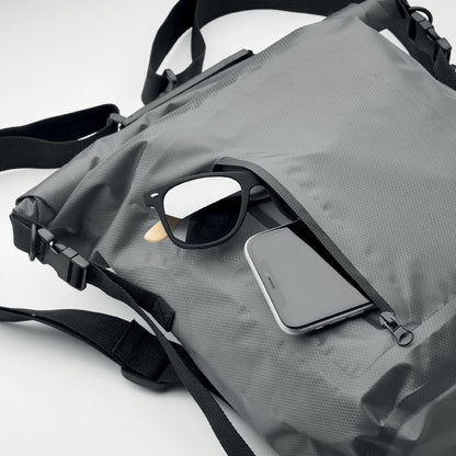 Detalle de movíl y gafas de sol dentro de bolsillo exterior con cierre cremallera de mochila gris de cierre enrrollable
