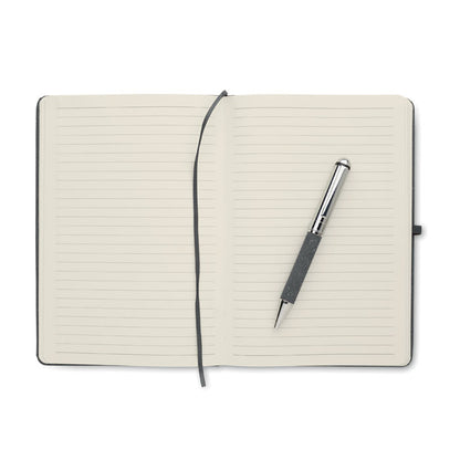 Libreta abierta con hojas crema, marcapáginas y boli negro y plata