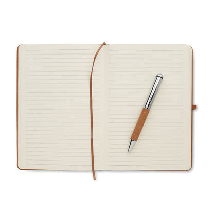Libreta abierta con hojas crema, marcapáginas y boli marrón y plata
