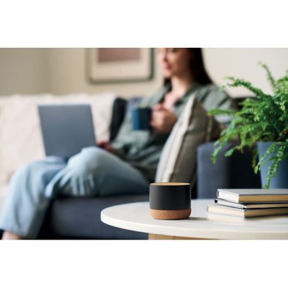 Altavoz negro de metal con base de corcho sobre mesa de salón