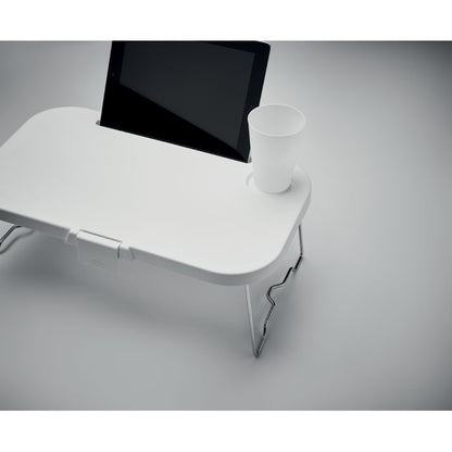 Mesita plegable con tablet y vaso sobre fondo gris