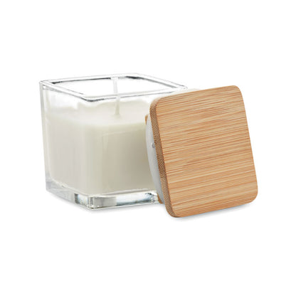 Vela cuadrada blanca con envase de vidrio y tapa de madera a un lado