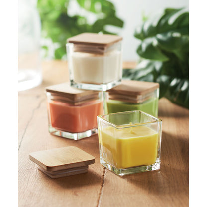 3 velas, amarilla, blanca y naranja con tapas de madera sobre mesa