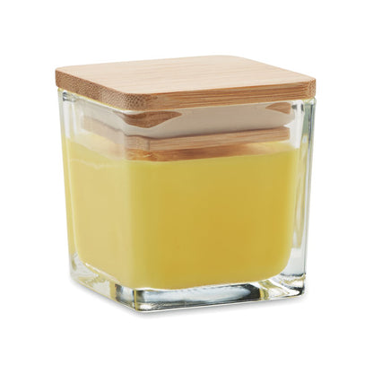 Vela cuadrada amarilla con envase de vidrio y tapa de madera