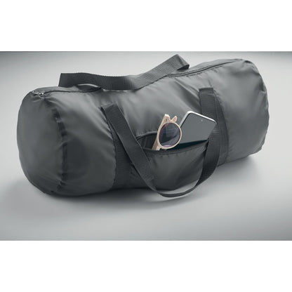 Bolsa gris de poliéster con bolsillo exterior con unas gafas de sol y un teléfono móvil dentro