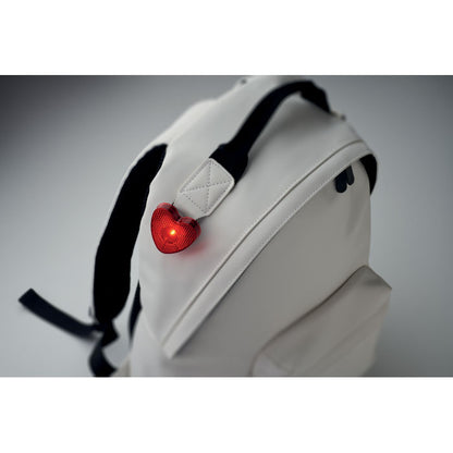 Reflector rojo en forma de corazón enganchado en asa de mochila