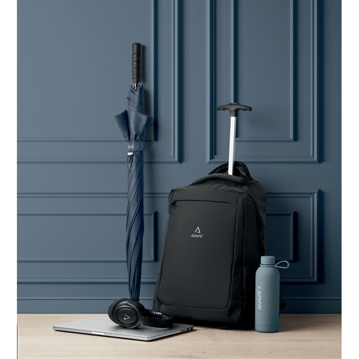 Mochila trolley RPET 600D negra con compartimento para portátil y otros accesorios, junto a un paraguas y laptop plateada