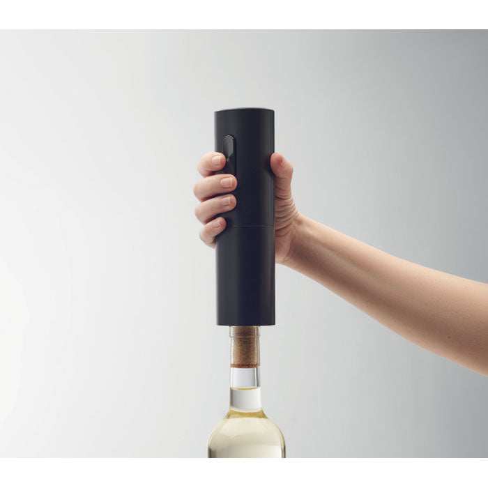 Mano utilizando un abridor eléctrico de botellas negro mate sobre una botella de vino, mostrando su diseño práctico.