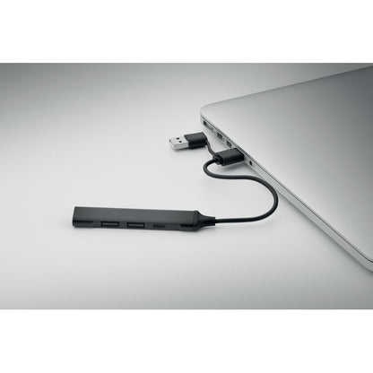 Hub USB con cuatro puertos y cuerpo de aluminio reciclado conectado a portátil.