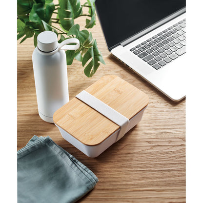 Set para llevar la comida con botella blanca y fiambrera sobre mesa de oficina