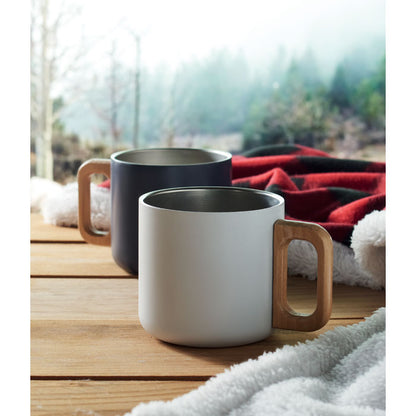Taza blanca y taza negra con asas de madera sobre mesa de madera en ambiente hogareño