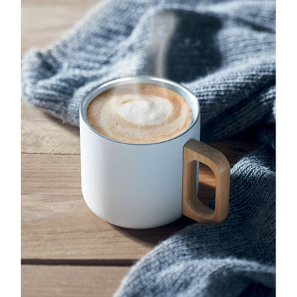 Bebida humeante en taza de acero blanca con asa de metal 