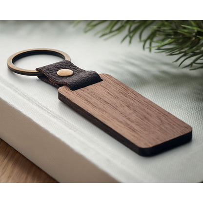 Detalle de aro metálico dorado y tira de PU marrón de llavero de madera rectangular