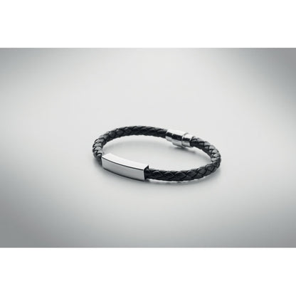 Vista superior de brazalete de piel y acero sobre fondo gris