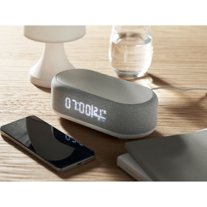 Altavoz inteligente gris con display digital frontal y superficie de carga inalámbrica
