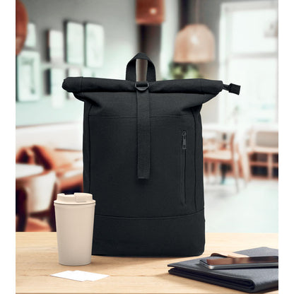 Perfil de mochila negra con cierre roll top sobre mesa