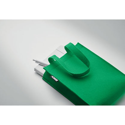 Libreta y bolígrafo blanco dentro de bolsa de fieltro verde con asas cortas
