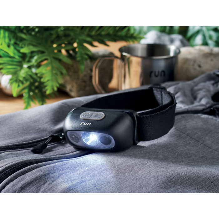ELYDEE - Linterna frontal recargable sobre una chaqueta con luz LED encendida.