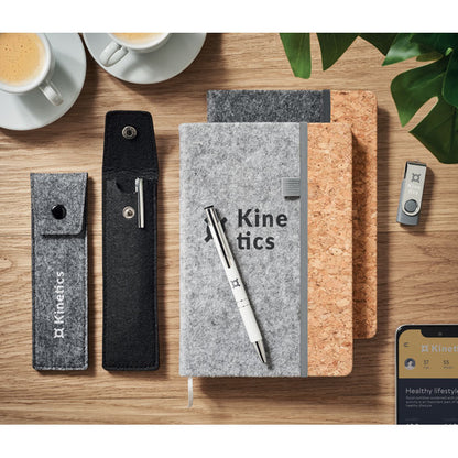 Estuches y libreta de fieltro con tazas de café sobre mesa de madera