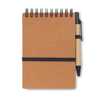 Cuaderno de tapas de cartón, cierre con goma elástica, encuadernación en la parte superior con espiral negra y con bolígrafo de cartón con clip, punta y pulsador negro unido a la libreta con una goma negra