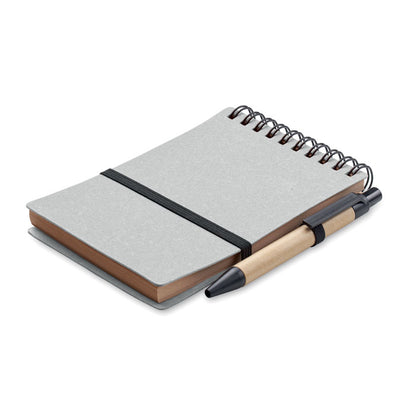 Libreta de tapas de cartón reciclado color gris, espiral WireO negro en la parte superior, cierre con goma elástica negra y soporte de goma con bolígrafo de cartón y pulsador, clip y punta de plástico negro