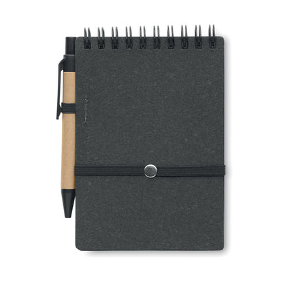 Parte trasera de libreta de cartón negra con espiral negra en la parte superior y cierre de goma negra y con bolígrafo de cartón y detalles negros en la parte izquierda