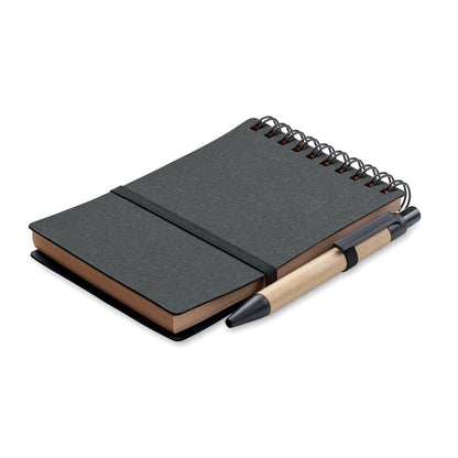 Libreta de tapas de cartón reciclado negro, espiral WireO negro en la parte superior, cierre con goma elástica negra y soporte de goma con bolígrafo de cartón y pulsador, clip y punta de plástico negro