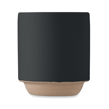 Vista frontal de taza negra de ceramica con parte inferior de color arcilla