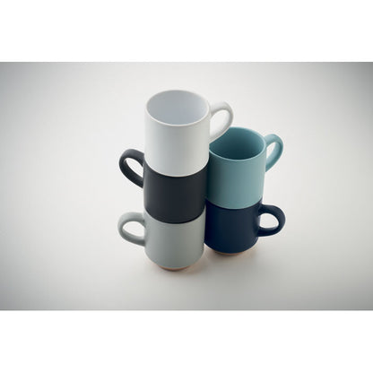 Bodegón de tazas de cerámica de colores apiladas una sobre otra sobre un fondo gris neutro