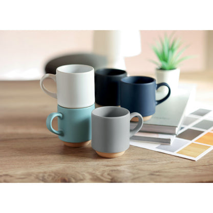 Mugs de cerámica de colores apiladas sobre una mesa de madera  
